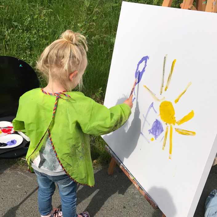 Barn maler ute på staffeli